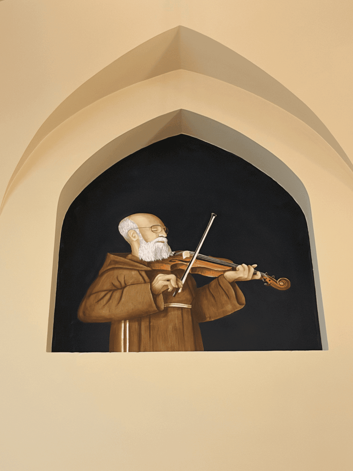 A statue of Solanus Casey playing his violin in a niche